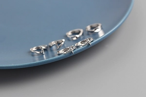Close-up of S925 sterling silver hoop earrings with cross charms on a blue ceramic plate