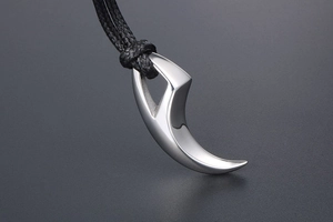 Detailed view of a silver crescent wolf tooth pendant with a black woven cord necklace