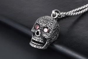 Macro shot of silver gothic skull pendant with red gemstone eyes and intricate carvings