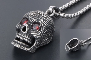 Macro shot of silver skull pendant with red gemstone eyes and floral carvings