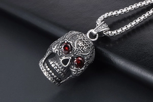 Close-up of punk skull pendant with red gemstone eyes on a textured silver chain