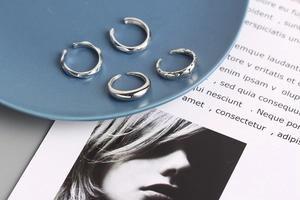 Set of four minimalist silver rings featuring wave and textured patterns on a blue tray
