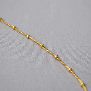 Dettaglio macro di catena a sfere in ottone placcato oro 18K con finitura lucida