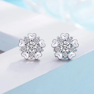Macro view of silver snowflake stud earrings with heart-shaped petals and white zircon