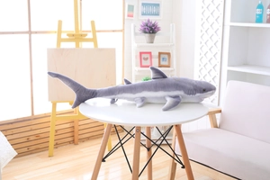 Detail of a soft gray and white shark plush pillow placed on a white round table