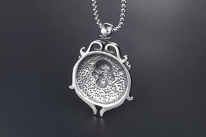 Detail shot of vintage silver skull pendant with rudder design and dotted texture back