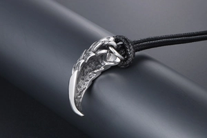 Detailed view of silver dragon scale tiger tooth pendant with black cord necklace