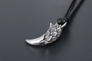 Macro shot of silver dragon scale tiger tooth pendant with textured metal details