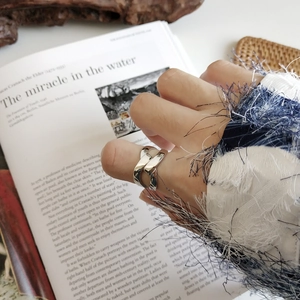 Detail of 925 sterling silver knotted wide band ring on hand with artistic background
