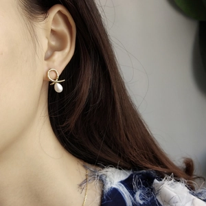 Detailed view of irregular 925 silver gold twist earrings with drop-shaped white pearls