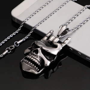 Pendentif crâne argenté style punk avec chaîne torsadée sur surface noire réfléchissante
