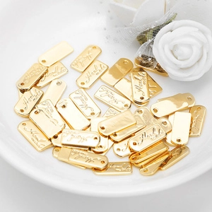 Macro shot of rectangular gold handmade metal tags on a white decorative ceramic tray