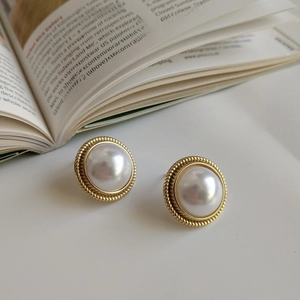 Close-up of 925 sterling silver shell pearl earrings with vintage gold rope edges
