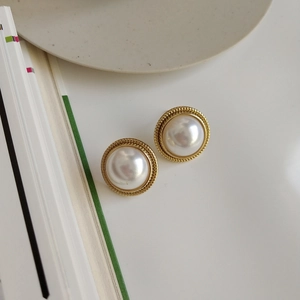 Detail view of retro gold twist edge pearl stud earrings with polished finish