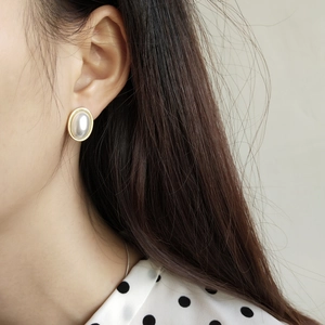 Close-up of vintage oval pearl earrings with gold bezel on model for an elegant look