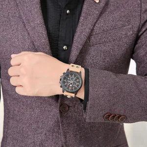 Close-up of black chronograph watch dial with khaki riveted leather strap on wrist