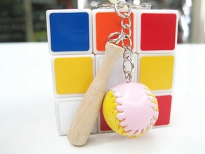 Macro shot of mini wooden baseball bat keychain with pink and yellow leather ball charm
