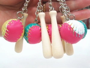 Detail of wooden baseball bat keychain and colorful leather balls held in hand