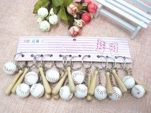 Detailed view of mini baseball bat and ball keychains with red stitching on display card