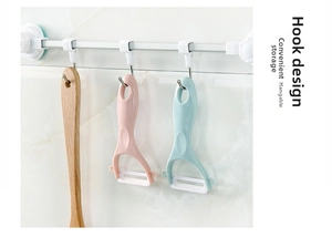 Pink and blue ceramic peelers with hanging hole design on a kitchen wall rack