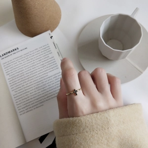 Detail of a minimalist gold ring with a black zircon cross on a soft lifestyle background