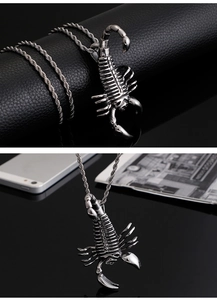 Detail shot of silver hiphop scorpion pendant with twist chain on black leather background