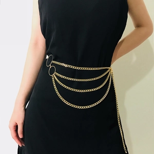 Detail of layered gold metal waist chain featuring multi-row chains and double ring charms