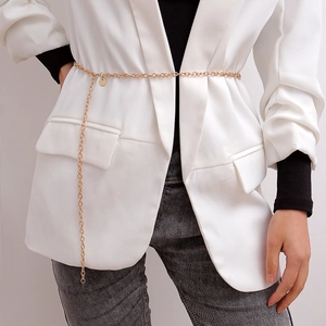 Detail of a multilayer gold metal body chain with round pendant over a white blazer