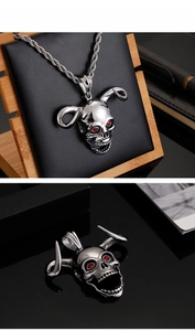 Detailed view of silver punk skull pendant with long horns and red gemstone eyes