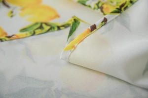 Detailed macro view of white linen tablecloth with fresh yellow lemon print and fine stitching