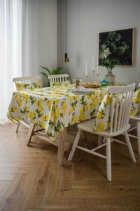 Detail of yellow lemon print cotton linen tablecloth and matching chair cushion in a cozy dining room