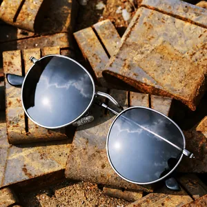 Retro round polarized sunglasses with silver metal frame and dark grey lenses on industrial background