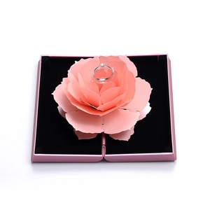 Close-up of a pink rotating rose jewelry box opening to reveal a ring holder