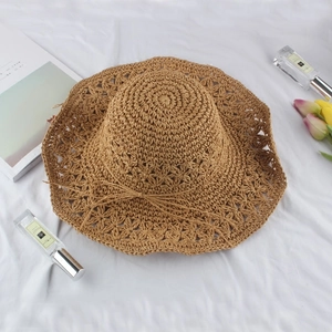 Elegant wide brim straw sun hat with woven floral patterns and bow on white fabric