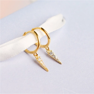 Macro shot of gold hoop earrings with sparkling diamond-set triangle pendants on silk