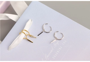 Close-up of gold and silver triangle drop earrings with cubic zirconia on a gift box