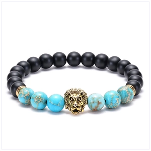 Detailed close-up of matte black beads and turquoise bracelet with golden lion head