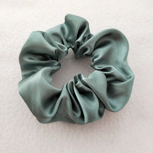 Detail of grey-green satin scrunchie showing silky texture and high elasticity