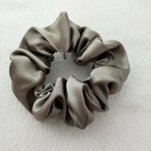 Close-up of grey satin scrunchie showing smooth silk texture and elegant fabric folds