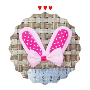 Pink polka dot and light pink bow hair clip shown with a ruler for size reference