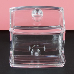 Macro view of clear acrylic cosmetic organizer with a lid and bottom dispensing slot