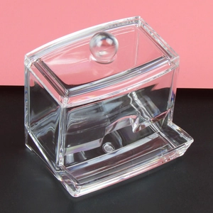 Close-up of clear acrylic cotton pad holder with lid on pink and black background