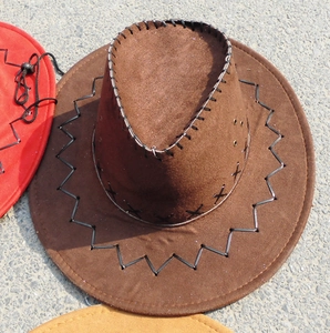 Detail of brown faux suede cowboy hat showing black cross-stitch seam and metal vent eyelets
