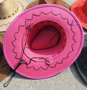 Detail of colorful cowboy hats with decorative cross-stitching and adjustable wind ropes