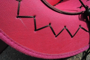 Detail of hot pink cowboy hat featuring black cross-stitch edges and textured finish