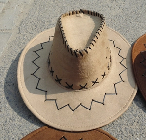 Detail of western cowboy hat with coarse black cross stitching on khaki suede fabric