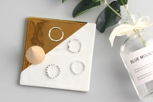 Detail of silver S925 rings set featuring wavy, twisted, and rhinestone textures on tray