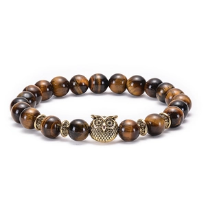 Macro shot of tiger eye beaded bracelet featuring a vintage golden owl charm and spacers