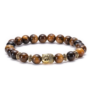 Macro view of Tiger Eye stone beads and a detailed golden Buddha head charm on the bracelet