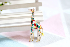 Detail view of a colorful giraffe brooch with enamel geometric patterns on a gold base